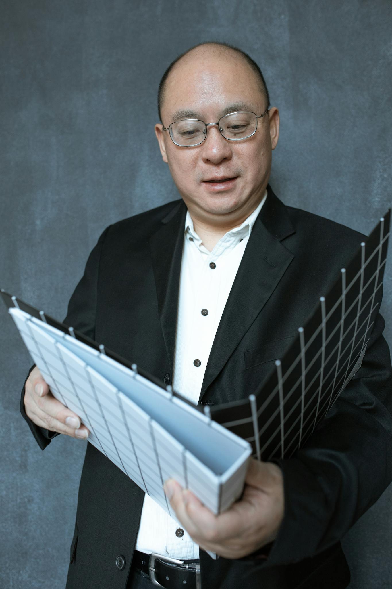 Businessman in glasses examines documents in a professional setting.