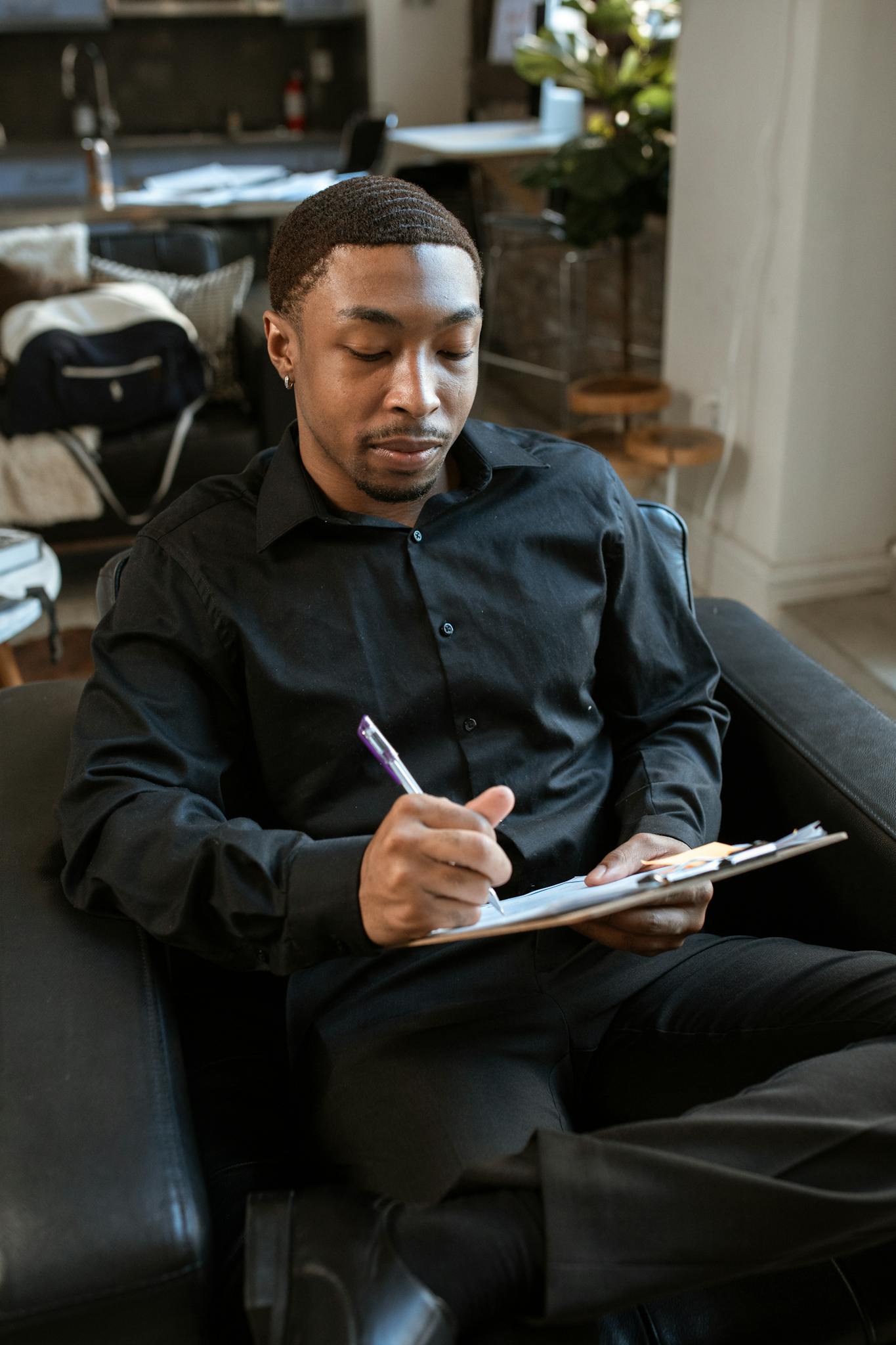 Professional man writing notes on clipboard during interview in office.